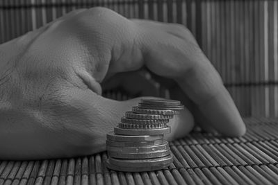 Cropped hand by stacked coins on table