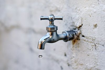 Close-up of water faucet against wall