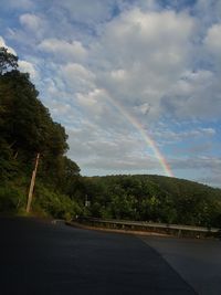 Rainbow over road against sky