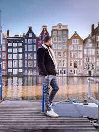 Full length of man standing by river in city