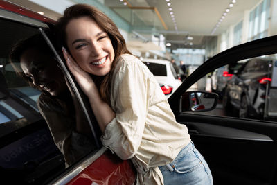 Happy woman embracing car in showroom