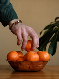 Close-up of hand holding orange on table