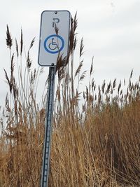 Road sign on field against sky