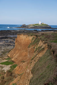 Lighthouse on beach by sea against sky