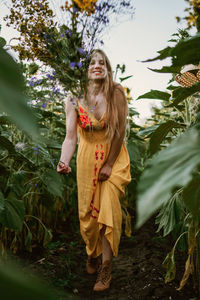 Young woman standing against plants