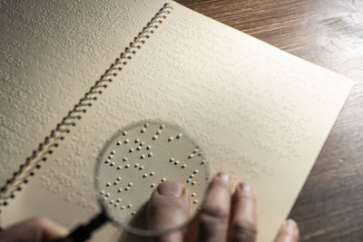 The focus of a magnifying glass on a page written in braille alphabet, the tactile reading system