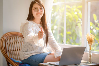 Young woman using phone while sitting at home