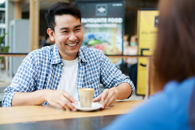 Portrait of a smiling young man sitting at table