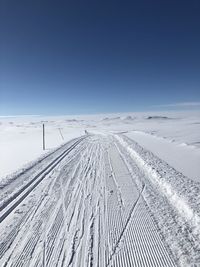 Snow covered land against clear blue sky