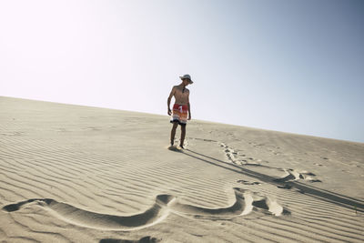 Full length of teenage boy standing at desert on sunny day