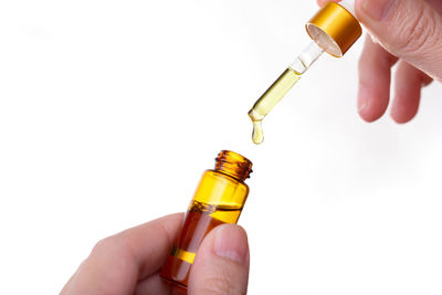 Close-up of hand holding glass bottle against white background