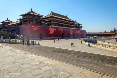 Group of people in front of building against clear sky