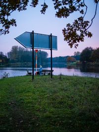 Lifeguard hut on field by lake against sky