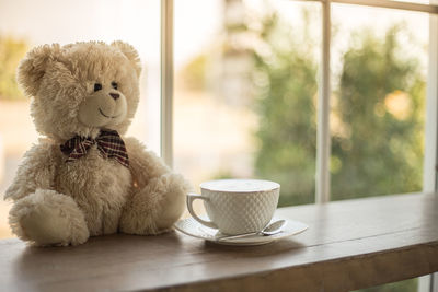 Close-up of teddy bear and coffee cup on table