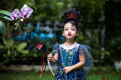 Cute little girl with expression face in halloween costume standing at at park.