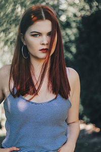 Portrait of beautiful woman standing against tree