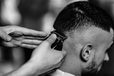 Cropped image of barber cutting man hair in shop