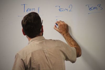 Rear view of businessman writing on whiteboard in office