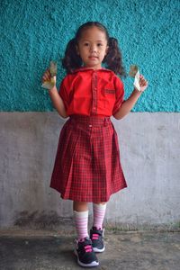 Portrait of a girl standing against wall. a girl has just started school. wearing a new uniform.