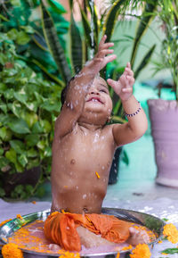 Cute toddler baby boy bathing in decorated bathtub at outdoor from unique perspective