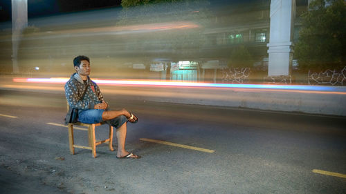 Blurred motion of man sitting at night