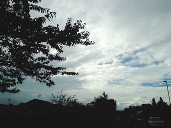 Low angle view of trees against cloudy sky