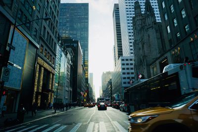 Vehicles on road amidst buildings against sky