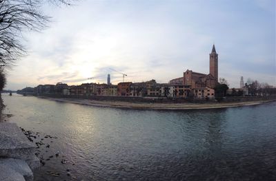 View of buildings by river against sky in city