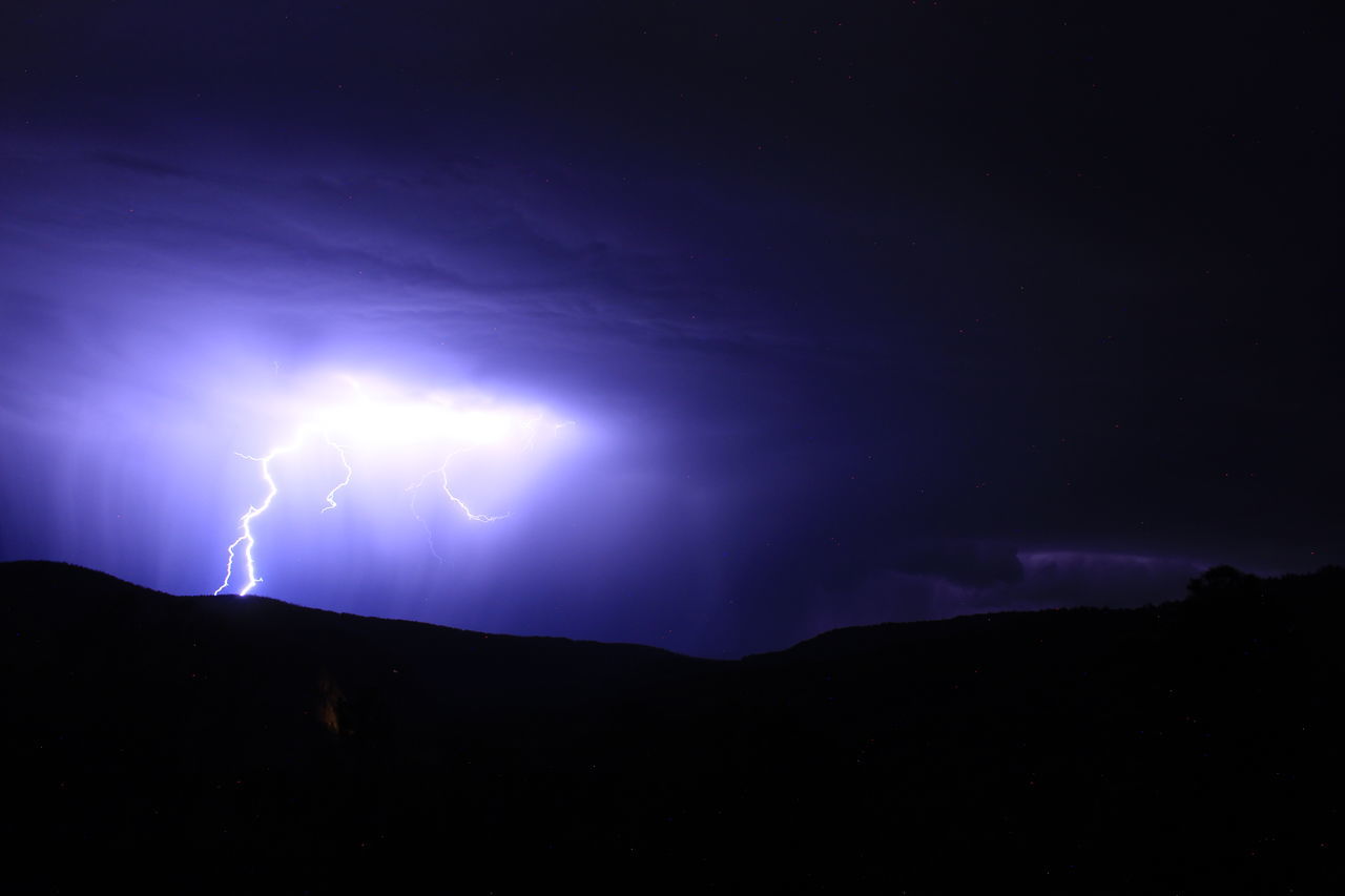 lightning, power in nature, storm, thunderstorm, night, beauty in nature, cloud, sky, thunder, environment, warning sign, dramatic sky, forked lightning, communication, sign, nature, scenics - nature, electricity, storm cloud, no people, silhouette, illuminated, dark, mountain, outdoors, darkness, light - natural phenomenon, landscape, awe, purple