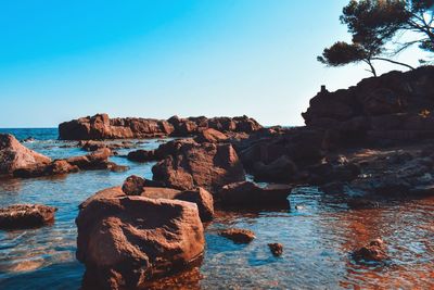 Rock formation on beach against clear blue sky