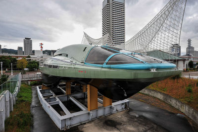 Boats moored in city by buildings against sky