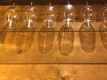 Low angle view of wineglasses hanging on wooden wall