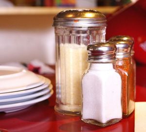 Salt and chili shakers on table