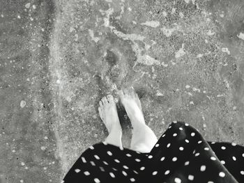 Low section of woman standing by swimming pool