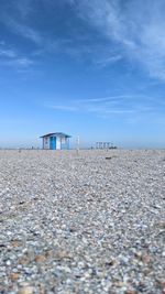 Empty beach with a single blue sea house under clear blue sky