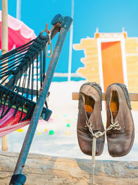 Pair of old brown leather shoes tied together with shoelaces hanging at the old vintage wooden pole 