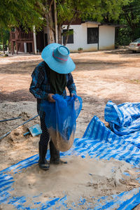 Full length of man holding sand in blue net at field