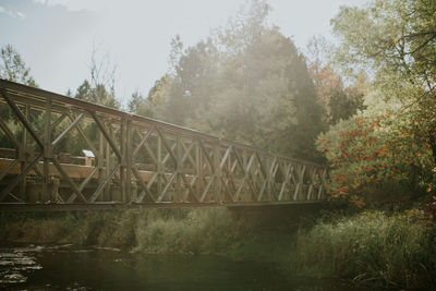 Bridge over river in forest against sky