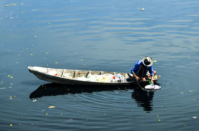 High angle view of man in boat collecting plastic