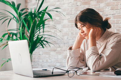 Girl with head in hands looking at laptop screen at home