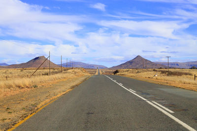 Road leading towards mountain against sky