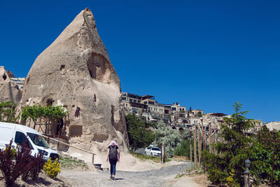 Woman traveler with backpack goes on the road to uchhisar in turkey