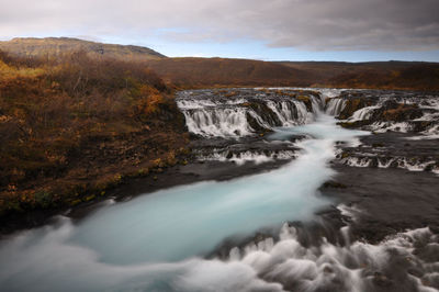 Scenic view of waterfall against sky