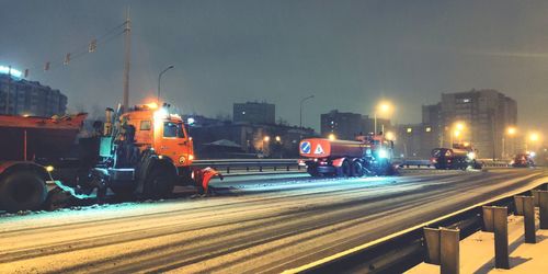 Cars on street against illuminated buildings in city at night