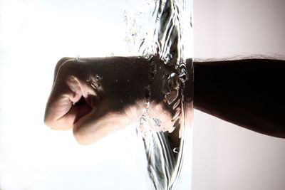 Close-up of fist in water against white background