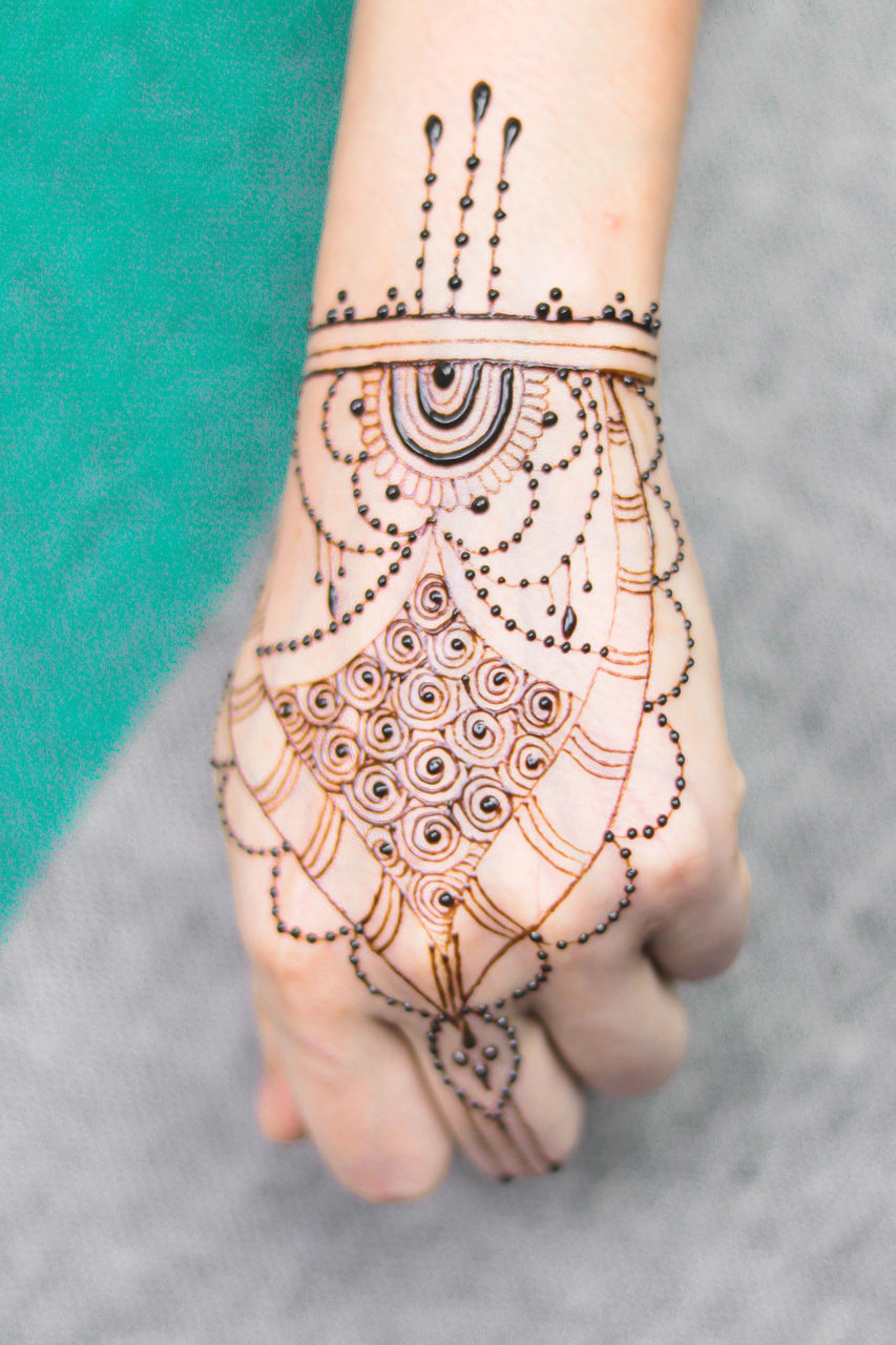 HIGH ANGLE VIEW OF WOMAN HAND WITH TATTOO ON TILED FLOOR