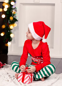 Portrait of cute girl playing with christmas tree at home