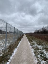 Road amidst field against sky