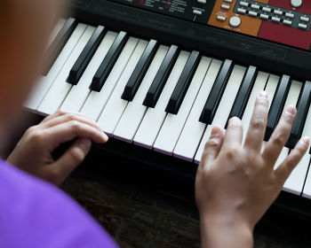 Happy cute boy playing piano at home