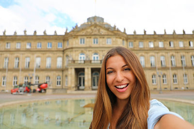 Portrait of smiling young woman against buildings